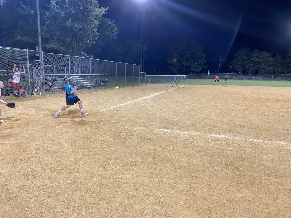 A group of girls playing softball in Richmond, Virginia at night.