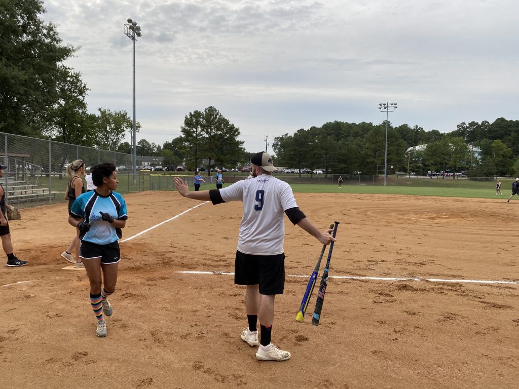 A group of people on a softball field taking Coed Rec Photos.
