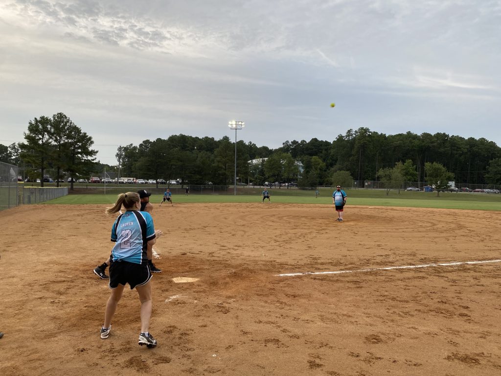 A group of people playing softball on a dirt field for RVA Softball Photos.