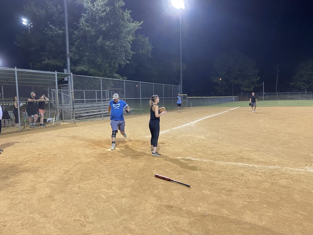 A group of people on a softball field at night, capturing NSA Softball Team Photos.