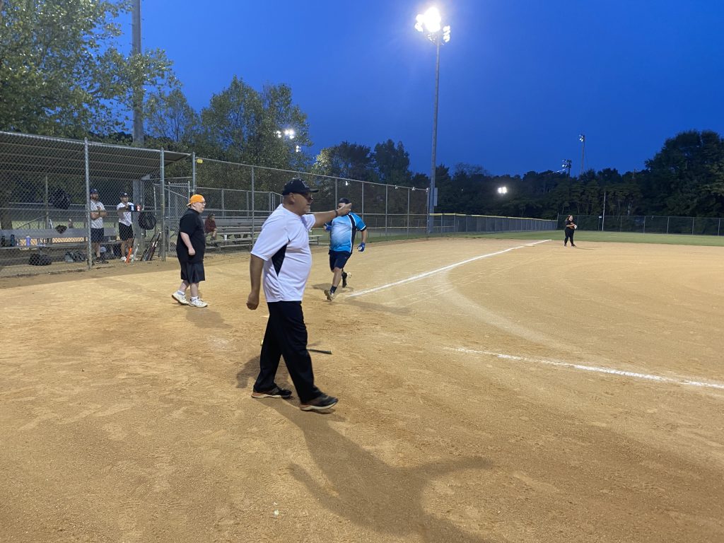 A group of people playing a game of coed softball.